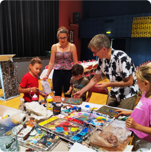 Phot pour la galerie du plasticien Pierre Quentel, dans cette photo on voit un groupe d'enfants qui entoure le peintre lors d'un atelier animé par le peintre sur thème fête en Afrique, en collaboration avec l'association à saint-sève