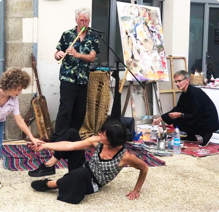 Photo utilisée pour la page mes actualité du peintre à Brest Pierre Quentel, et dans cette photo on voit le peintre accroupi entrain de mélanger sa peinture entouré d'un musicien et de deux spectateurs